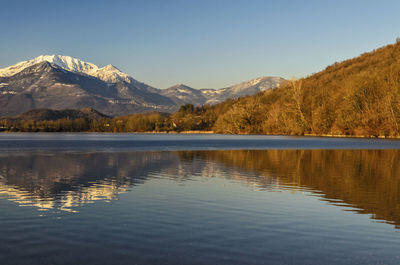 Scenic view of lake by snowcapped mountains against sky