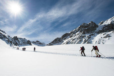 People skiing on snowcapped mountain against sky