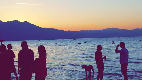 People on beach against sky during sunset