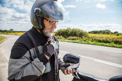 Man by motorcycle using phone on road