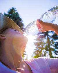 Close-up of woman drinking water against sky