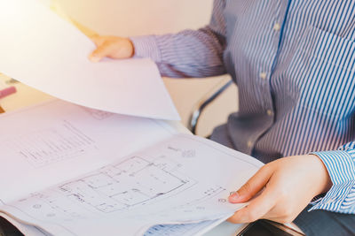 Midsection of man holding paper on table