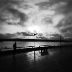 Pier on sea against cloudy sky