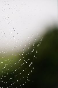 Close-up of water drops on windshield against sky