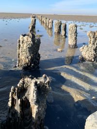 Rocks on shore at beach against sky