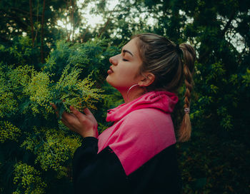 Side view of girl with plants against trees
