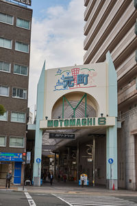 Road sign by buildings against sky in city