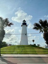 Lighthouse by building against sky