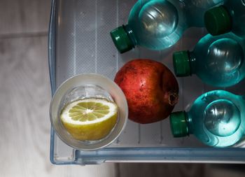 Directly above shot of water bottles with pomegranate and lemon in tray