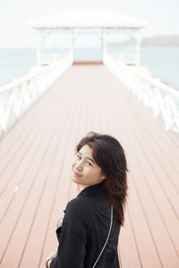 Portrait of young woman standing on pier