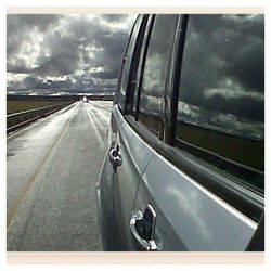 Cars on road against cloudy sky