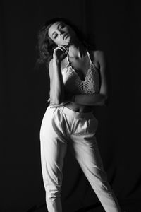 Young woman standing against black background