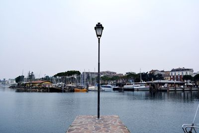 Sailboats moored in river by city buildings against sky