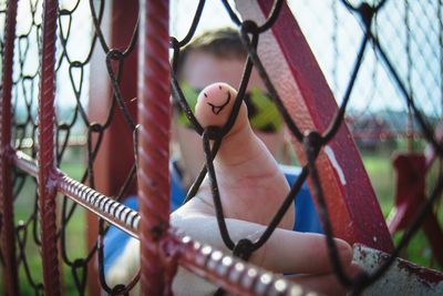 Cropped hand of man on chainlink fence