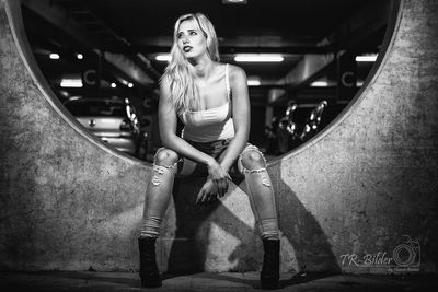 Full length portrait of woman sitting in corridor