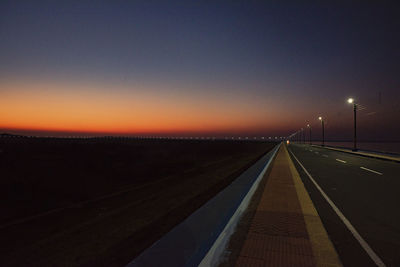 Empty road against sky at sunset