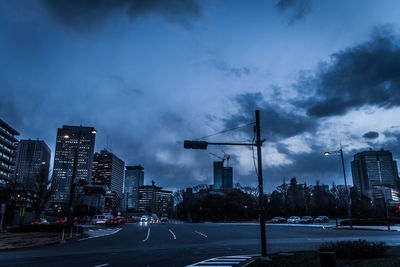 Traffic signal on road in city against sky