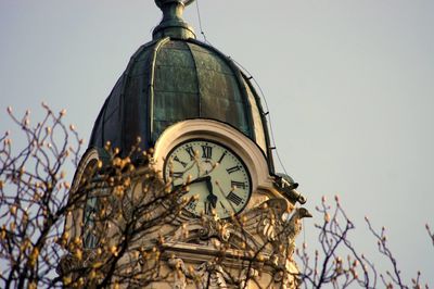 Low angle view of twigs against church clock tower