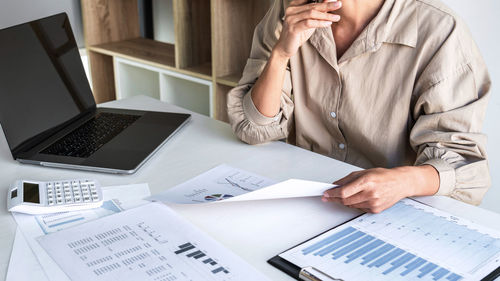 Midsection of businesswoman working at desk in office