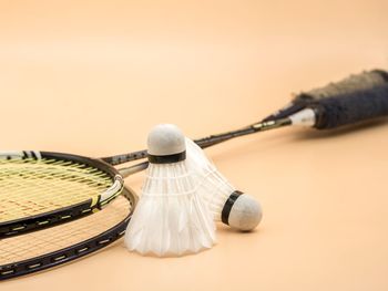 Close-up of shuttlecocks and rackets on beige background