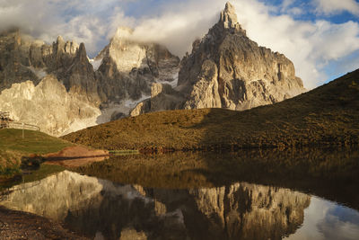 Scenic view of lake by mountains against cloudy sky