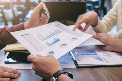 Close-up of colleagues discussing over graph at desk in office