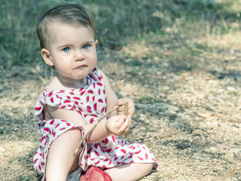 Portrait of baby girl sitting on field