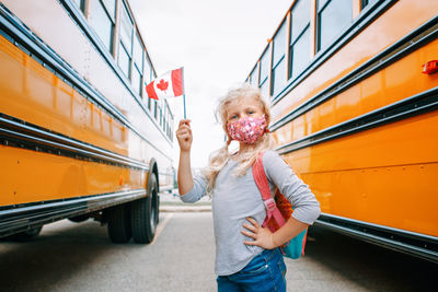Girl student with face mask holding canadian flag. student kid in new normal during coronavirus.