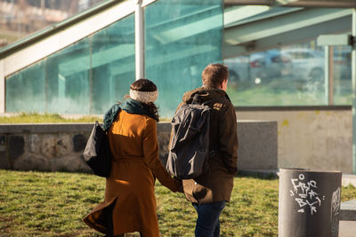 Rear view of men standing against built structure