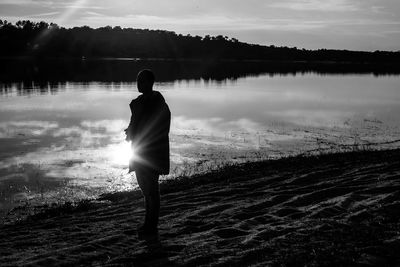 Rear view of silhouette man on lake against sky