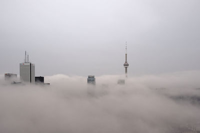 Communications tower in city against sky