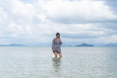 Full length of man standing in sea against sky