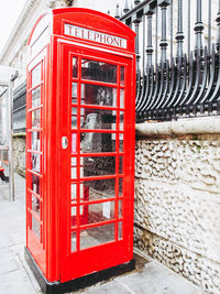 Red telephone booth on sidewalk in city