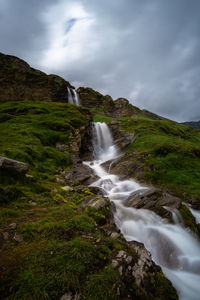 View of waterfall against cloudy sky