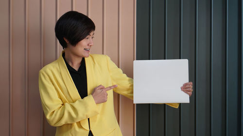 Woman standing against yellow wall