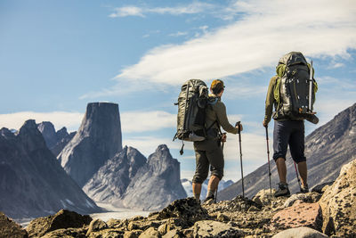 Two backpackers look out at view from mountain ridge.