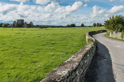 Road amidst field against sky