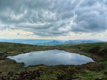 Scenic view of moorland pool against moody sky