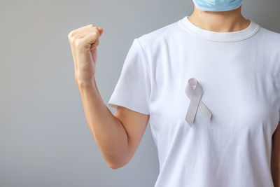 Midsection of woman with arms crossed against wall