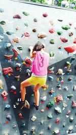 Young woman bouldering on climbing wall