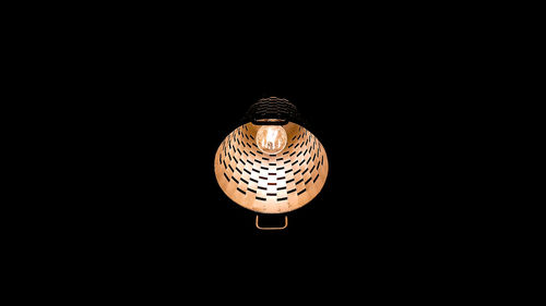Low angle view of illuminated lamp against black background