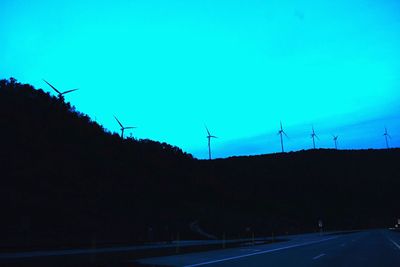 Silhouette of electricity pylons against clear blue sky