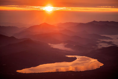 Scenic view of silhouette mountains against orange sky