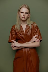 Portrait of young woman standing against wall