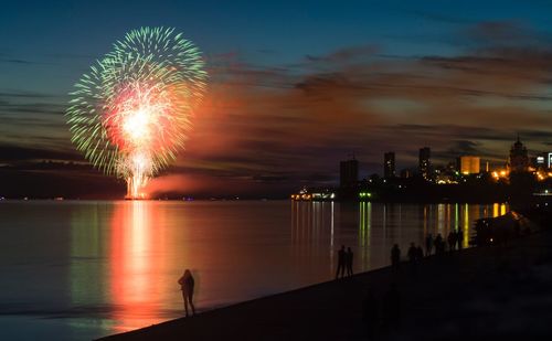 Firework display over river in city at night