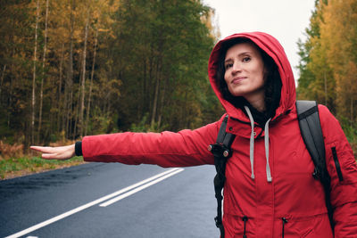 Portrait of smiling young woman standing by road