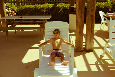 Shirtless boy relaxing on lounge chair