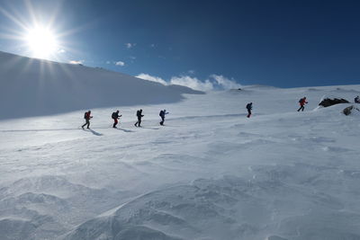 People skiing on snowcapped mountain against sky