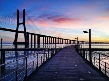 Pier over sea against sky during sunrise and vasco da gama bridge at tejo river