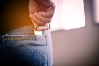 Midsection of person inserting coin in pocket